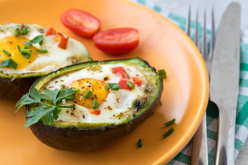 Eggs baked in avocado with bacon, red paprika and chive.