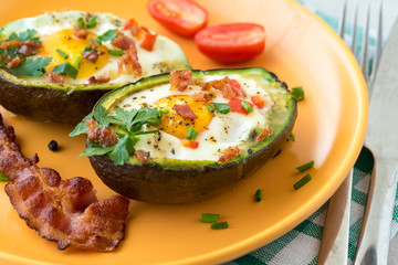 Eggs baked in avocado with bacon, red paprika and chive.