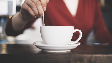 Close up of a woman barista drawing on coffee with a wooden stick. Coffee shop concept.