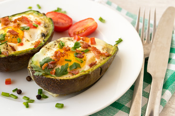Eggs baked in avocado with bacon, red paprika and chive.