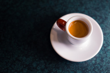 A cup of coffee is americano on a dark background.