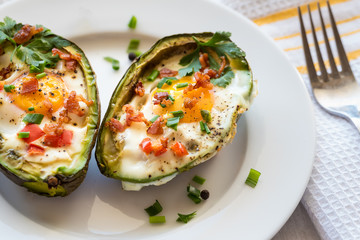 Eggs baked in avocado with bacon, red paprika and chive.