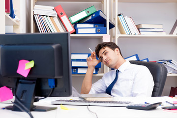 Businessman working in the office with piles of books and papers