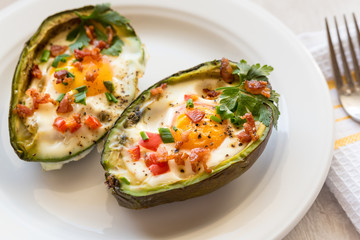 Eggs baked in avocado with bacon, red paprika and chive.