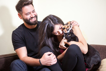 Gorgeous beautiful young couple holding cats in hands. Relax and love. Animal care. Animal lovers