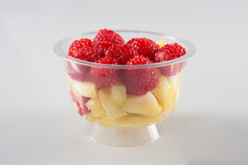 Healthy fruit salad in the plastic bowl isolated on white