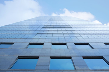 Clouds reflected and sunlight in windows of modern office building. 