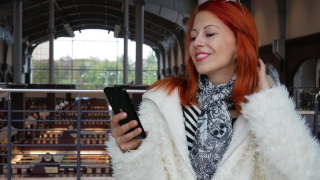 Beautiful red hair woman smiling and surfing internet shopping tour at supermarket