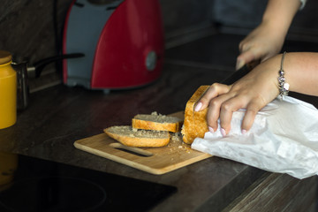 close up  female hands cutting white bread for toasts