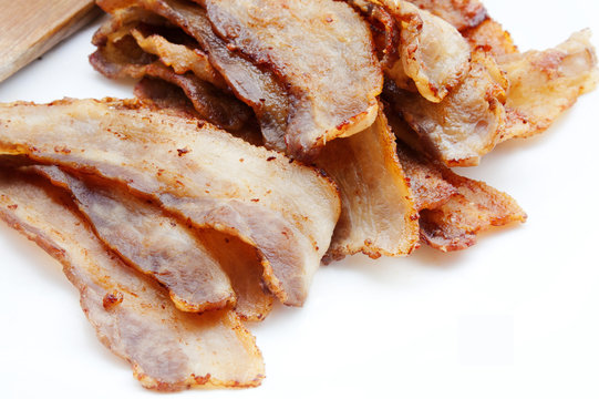 Fried pork bacon and wooden spatula on a white background
