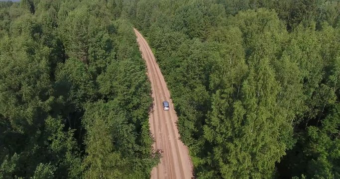 Pursuit of the vehicle from the air, flight after speed driving car on the dirt forest road