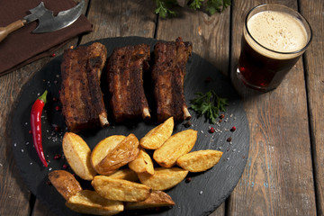 fried pork ribs with potatoes on a stone surface