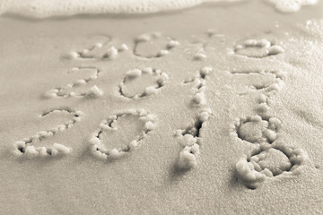 The concept of a new year on the beach. Handwritten inscription on the sand, 2018 replaces 2017