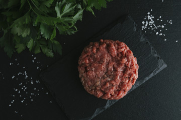 Tartare steak. Beef raw chopped meat with spices, herbs and egg yolk. Fresh, spicy, delicious, gourmet meal on dark background with copy space, close-up
