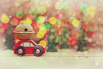 Miniature Red Car Carrying a Gift on roof on colorful bokeh background.