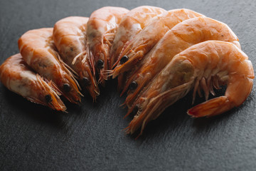 Shrimps on black background. Delicious seafood appetizer served boiled or grilled with spices. Close up. Top view