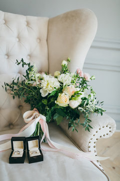 Rustic wedding bouquet and rings in the black box on a luxury sofa. Indoors. Artwork