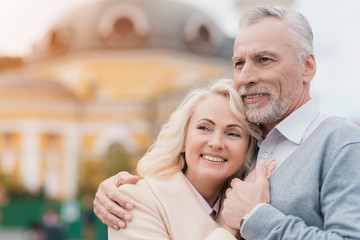 Mature couple posing. The man gently hugs the woman. They are smiling