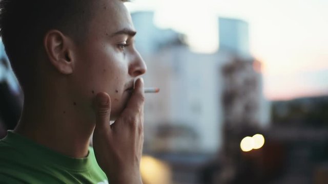 Handsome young man smoking cigarette outdoors, closeup the man smokes addicted nicotine problems in young age
