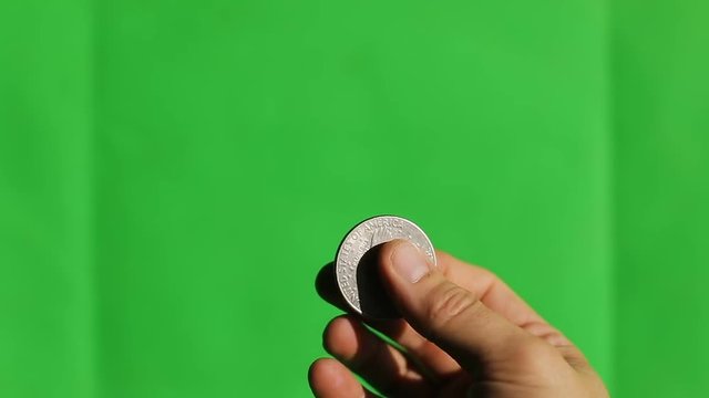 Man hand, holding one dollar coin on green screen chroma key chromakey and blured background liberty old coin