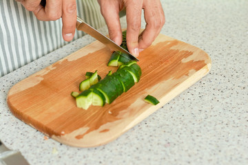 Hands cutting cucumber. Green vegetable close up.