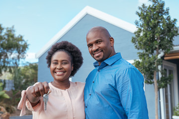 Smiling African couple holding the keys to their new home