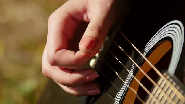 Woman playing acoustic guitar, closeup shot