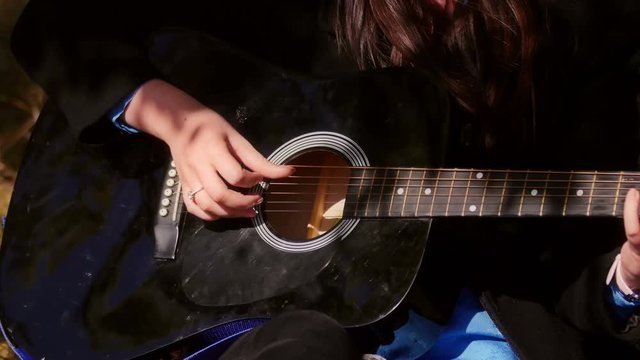 Woman playing acoustic guitar, closeup shot