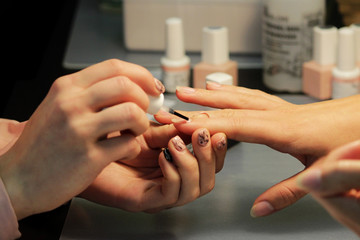 A student at the training courses of manicure applies base layer.