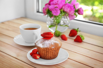 Delicious muffin and cup of tea on windowsill