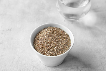 Bowl with chia seeds and glass of water on table