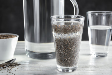 Glass of water with chia seeds on table
