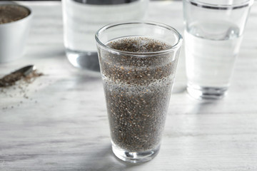 Glass of water with chia seeds on table