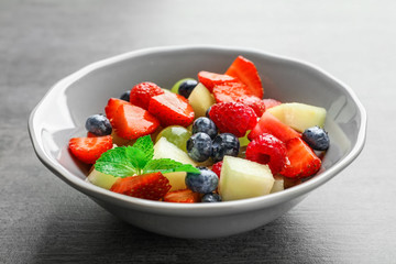 Bowl with yummy fruit salad on grunge table