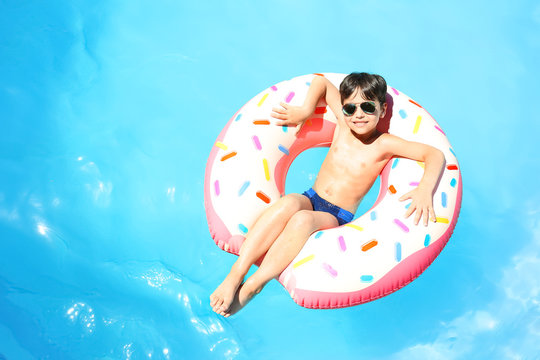 Cute little boy with inflatable donut in swimming pool