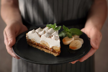Woman holding plate with delicious banana cake, closeup