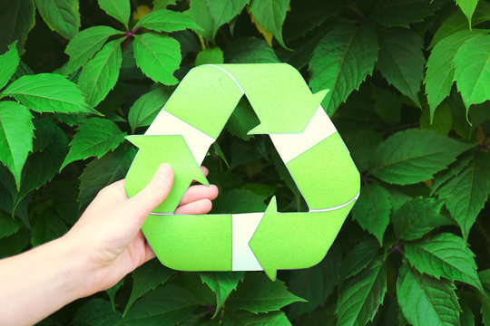 Woman holding symbol of recycling outdoors