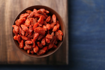 Bowl with red dried goji berries on wooden table