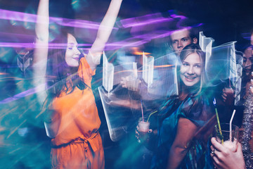 Happy friends dance party in motion. Joyful New Year company in night club, active Christmas celebration. Disco people in blurred colors, modern youth life
