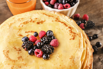 Stack of delicious thin pancakes served with berries, closeup