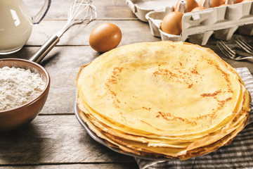 Plate with stack of delicious thin pancakes on kitchen table