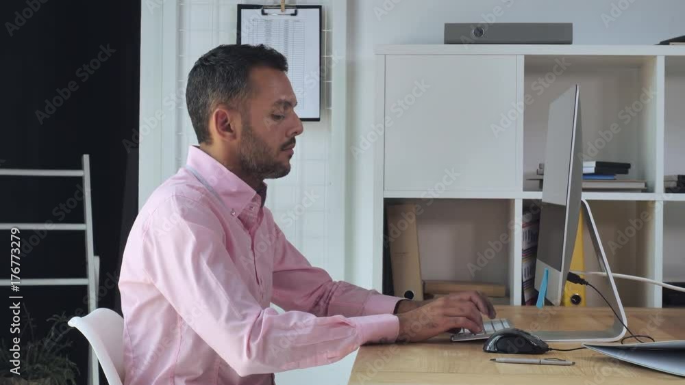 Poster Professional businessman typing on keyboard sitting at the desk with computer in home office. Mixed race entrepreneur working in room with casual interior