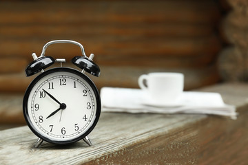 Fototapeta na wymiar Alarm clock on wooden bench outdoors. Morning routine concept