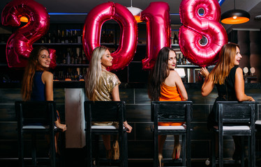 Fototapeta na wymiar New Year party at bar. Beauty females. Stylish women group, friends celebration. Club background, festive mood