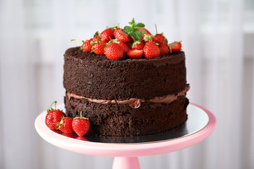 Delicious chocolate cake with strawberries on stand, closeup