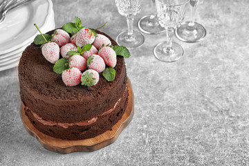Board with delicious chocolate cake on table