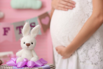 Cute toy bunny and blurred pregnant woman