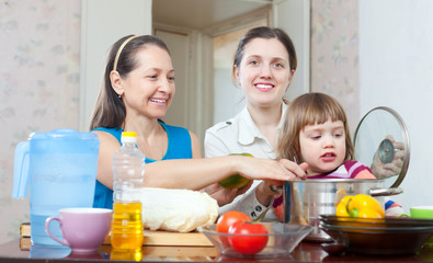 Obraz na płótnie Canvas Two happy women with child in kitchen