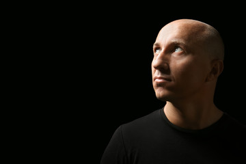 Bald man in t-shirt on black background