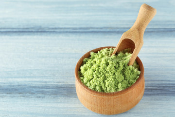 Bowl with wheat grass powder and scoop on wooden table